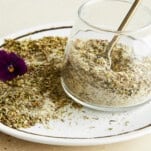 A jar of Greek seasoning on a plate.