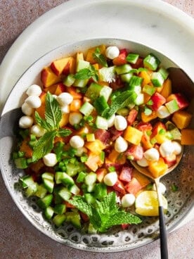 A bowl of peach salad with mozzarella pearls.