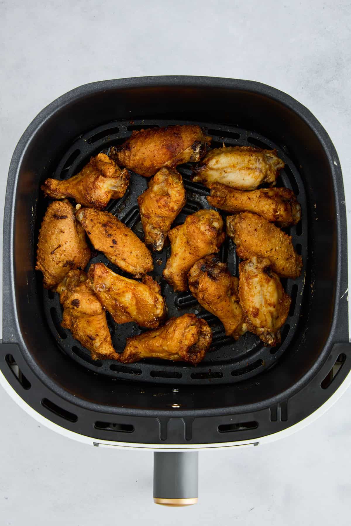 Cooked Air Fryer Garlic Parmesan Chicken Wings in an air fryer basket.
