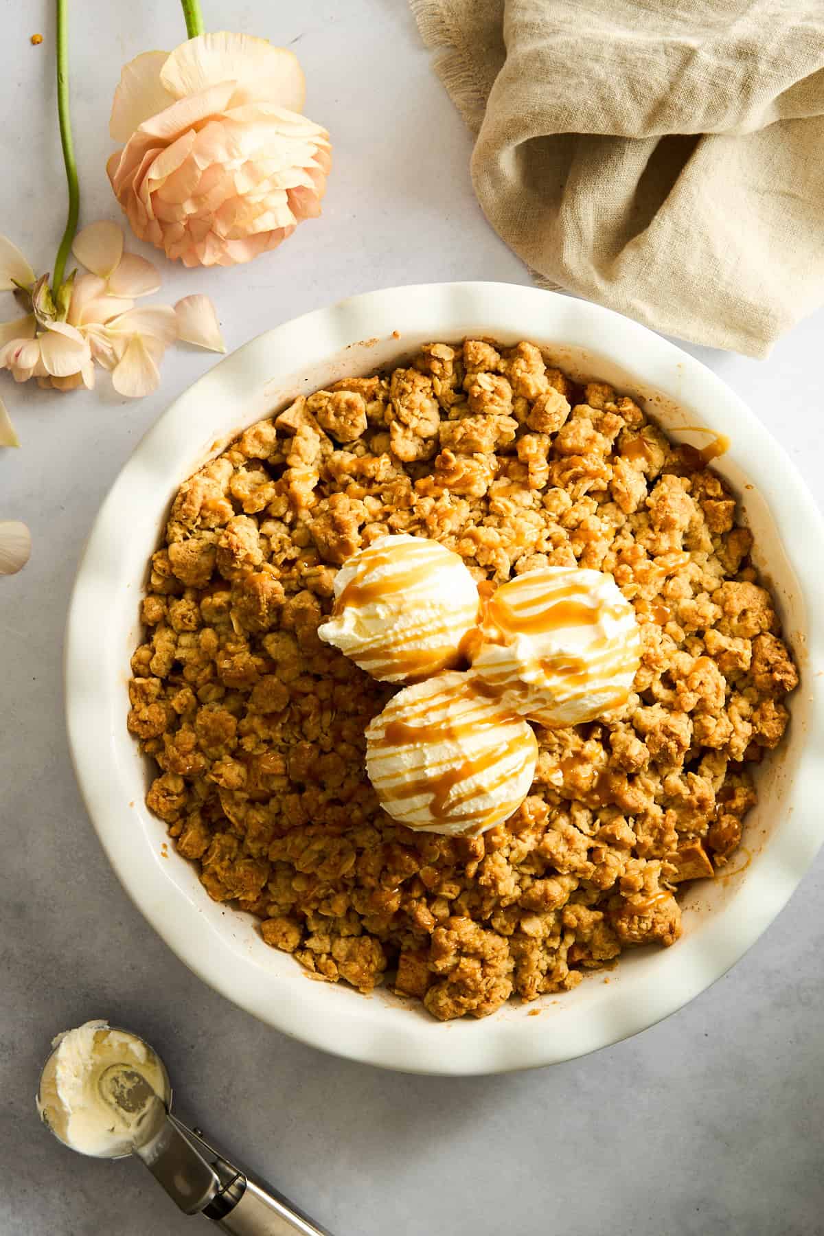 Apple crisp topped with vanilla ice cream and caramel sauce.