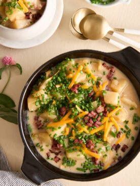 A bowl of cheesy potato soup topped with bacon, chives, and cheese.