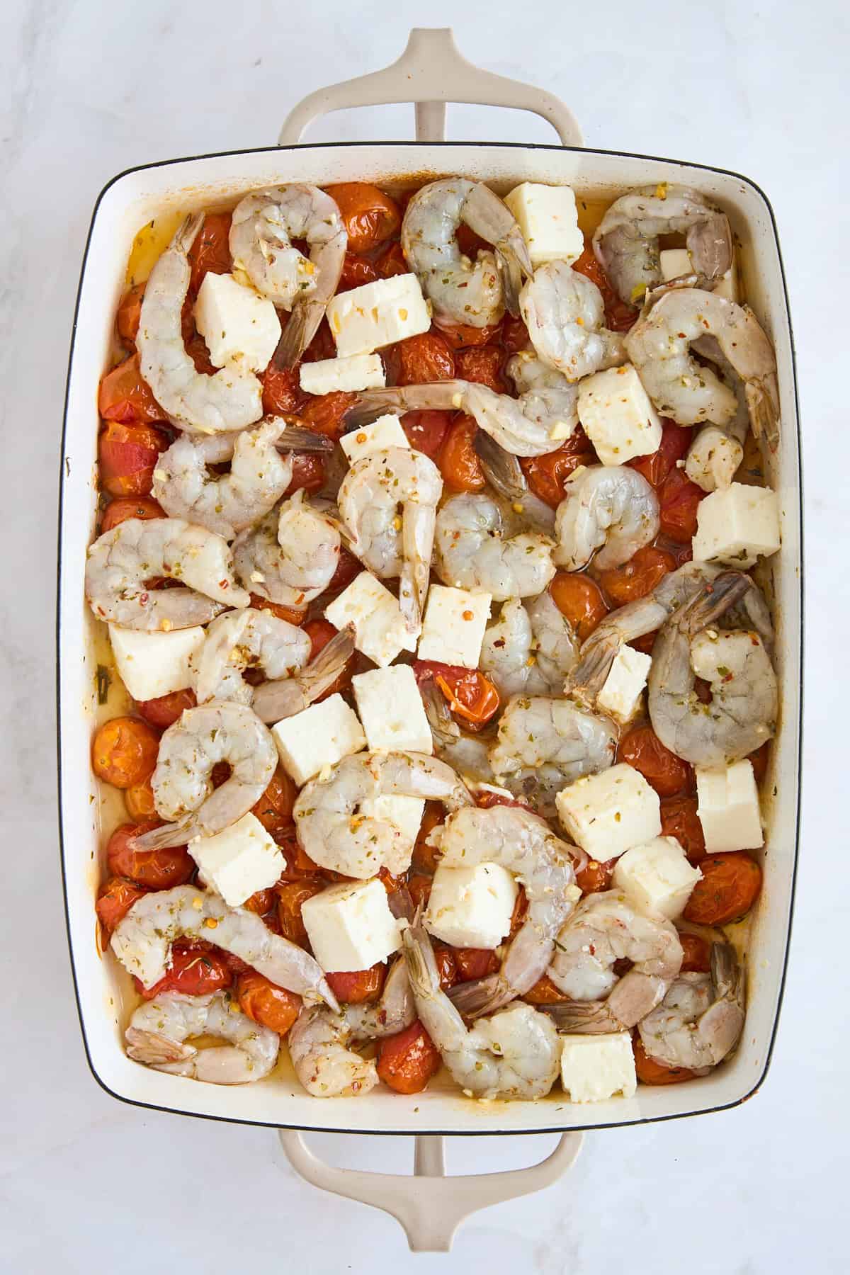 Baked tomatoes topped with feta cubes and raw shrimp.