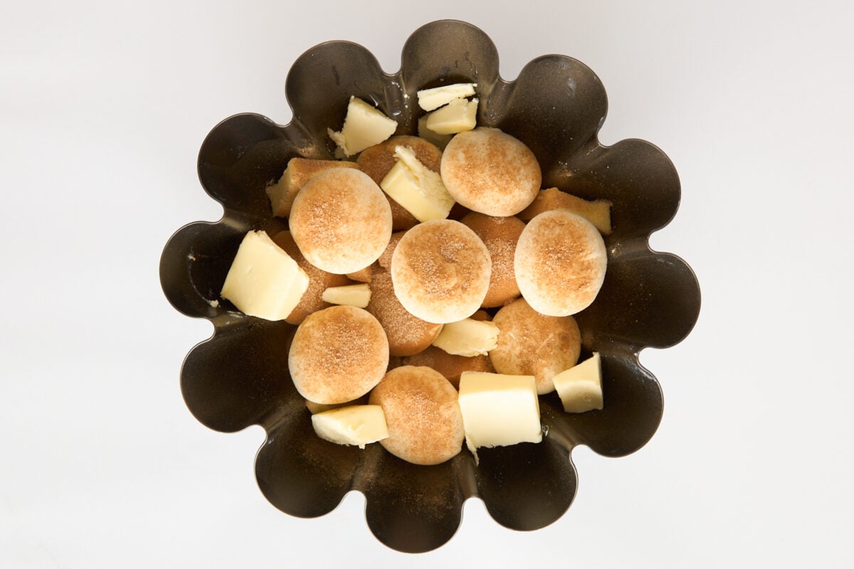 Unbaked rolls, butter, and cinnamon sugar in a bundt pan.