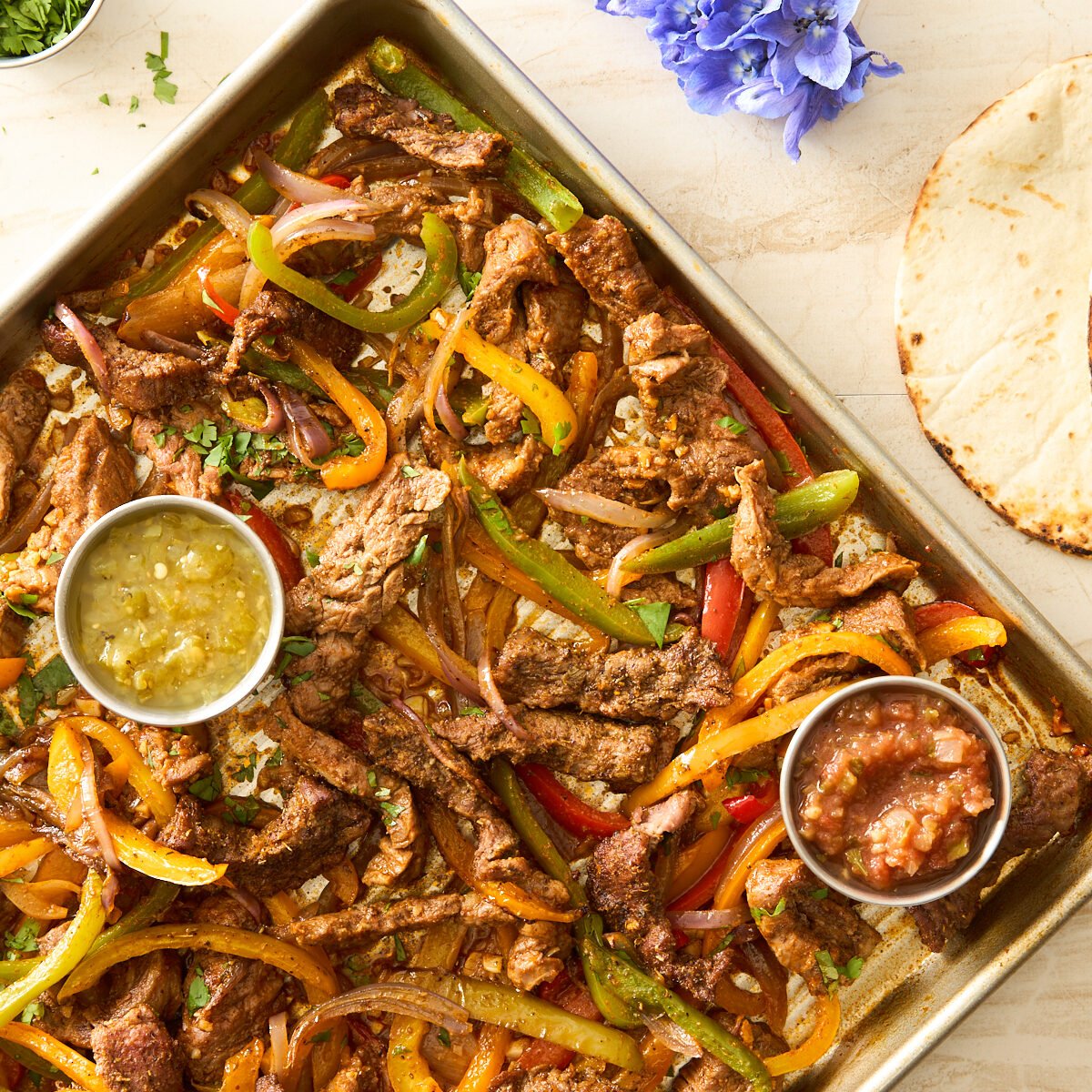 Sheet pan steak fajitas on a baking sheet.