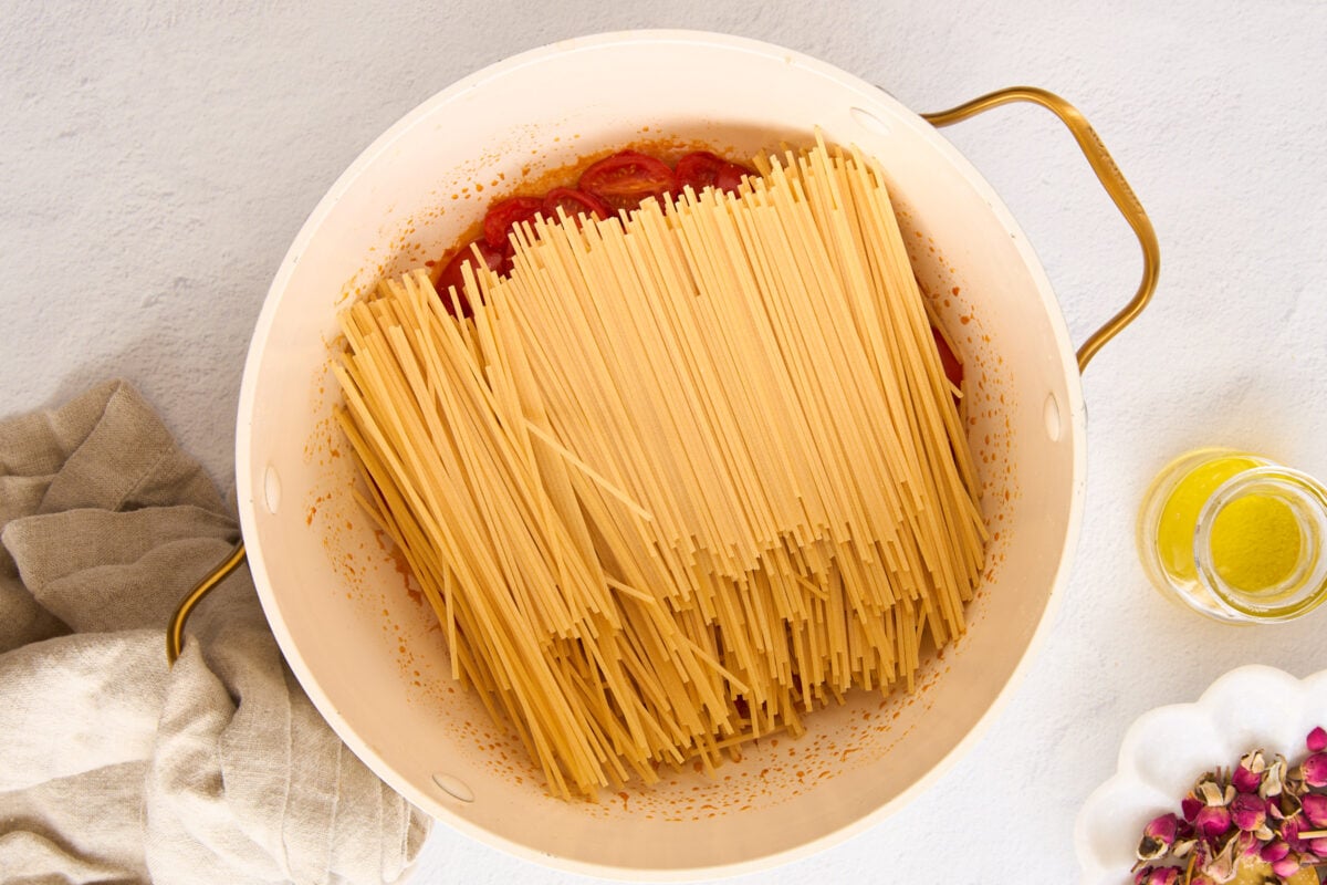 Pasta in a pot with tomatoes and garlic.