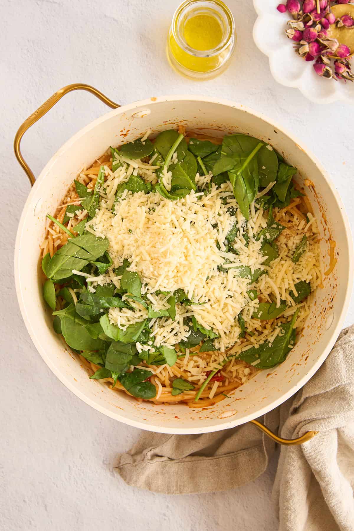 Spinach and cheese on top of cooked pasta in a pot. 