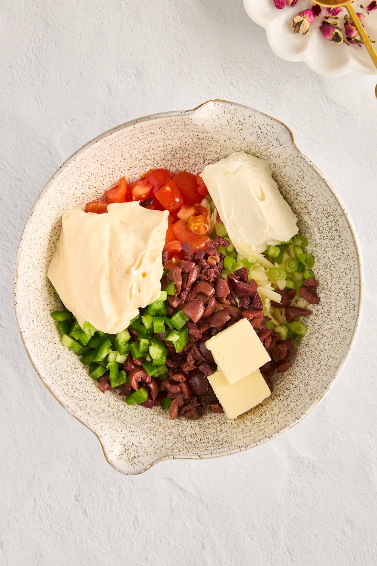 Bell peppers, tomatoes, olives, and cheese in a bowl. 