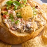 A sourdough bread bowl cheese dip bowl with a tortilla chip sticking out.