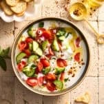 A bowl of cucumber and tomatoes with cottage cheese.