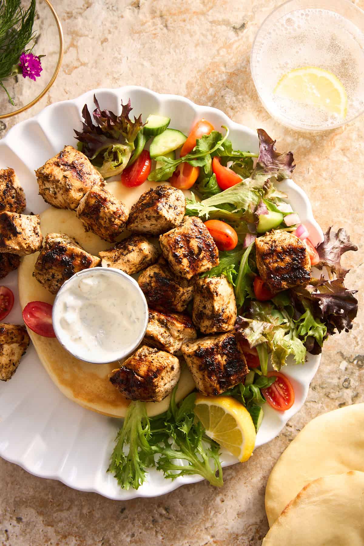 A plate of Mediterranean chicken with pita and salad. 