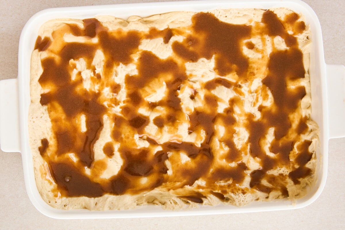 Cinnamon butter poured over raw dough in a baking dish.