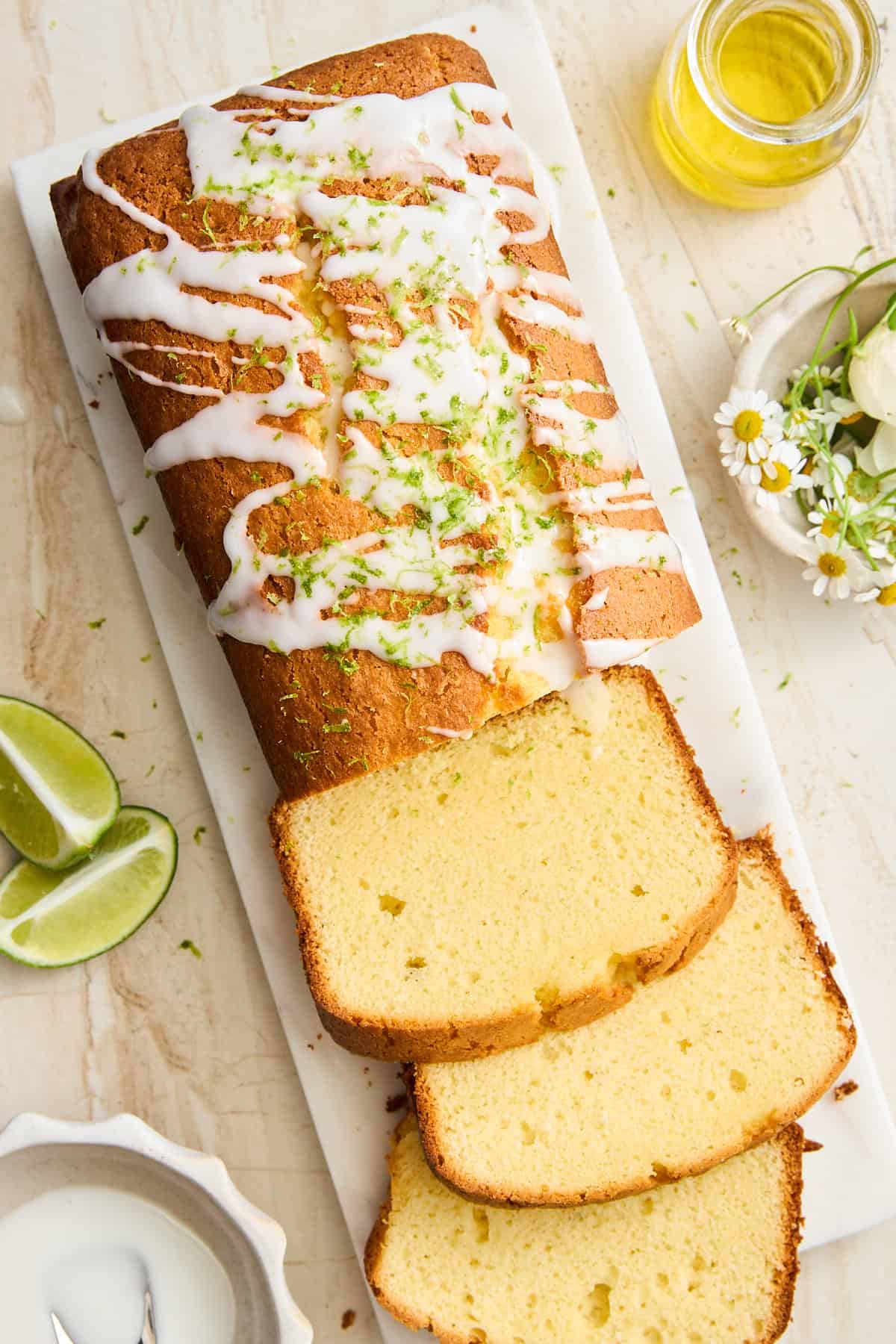 A key lime loaf with lime glaze on a cutting board with three slices cut. 