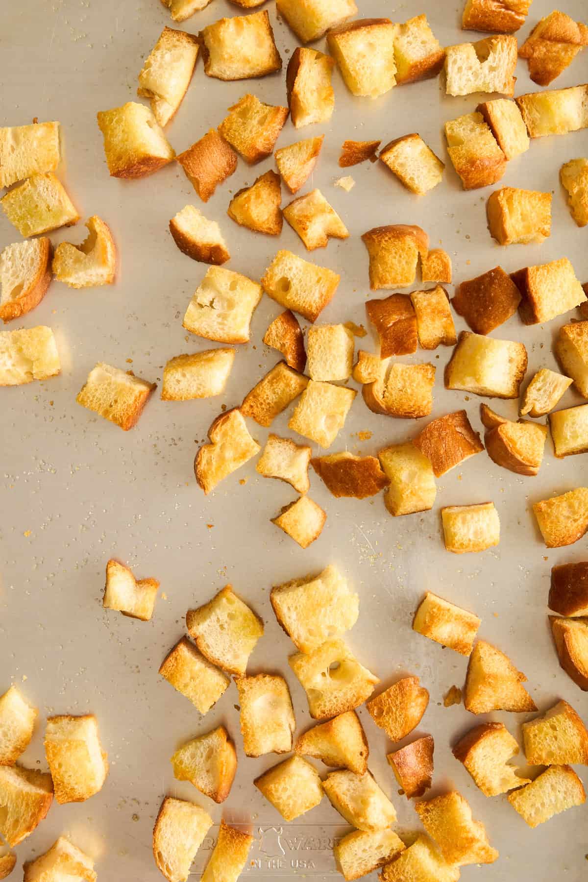 Toasted bread cubes on a baking sheet. 