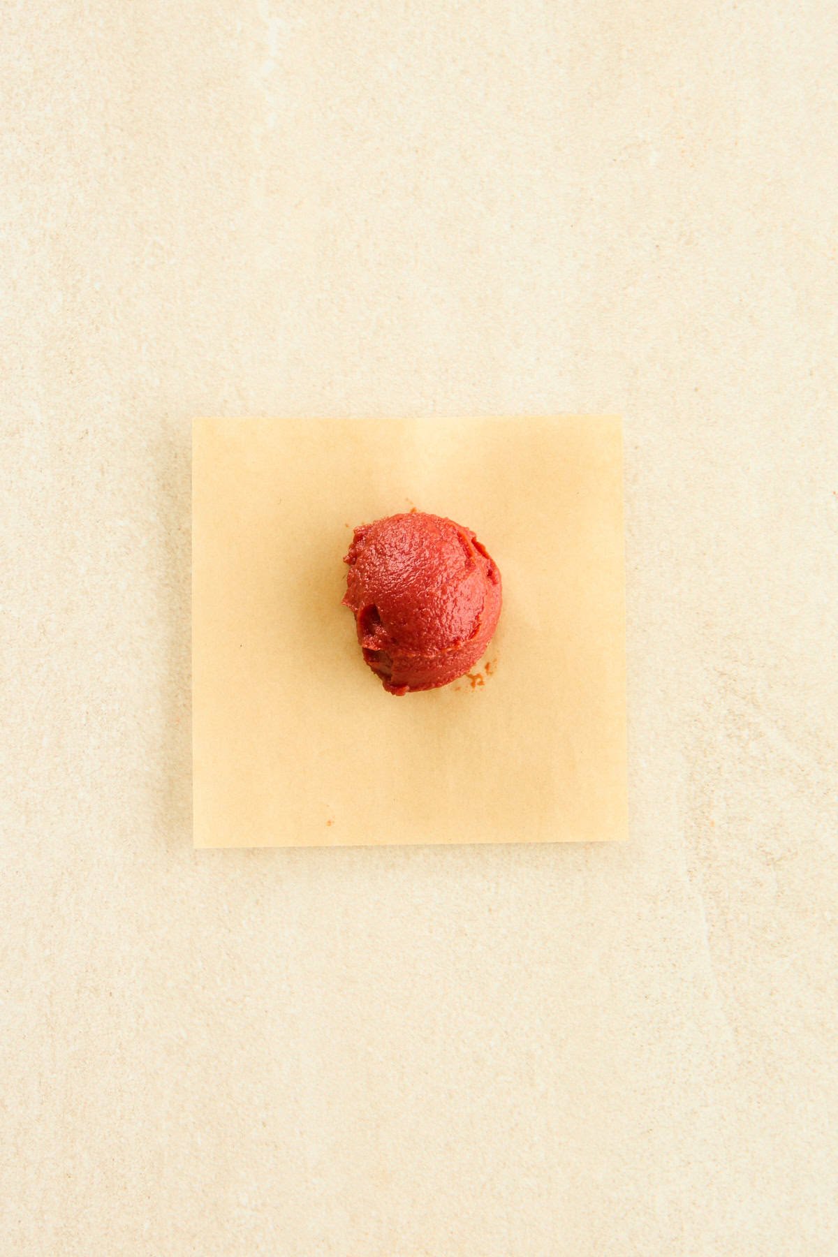 A tablespoon of tomato paste on a sheet of parchment paper. 