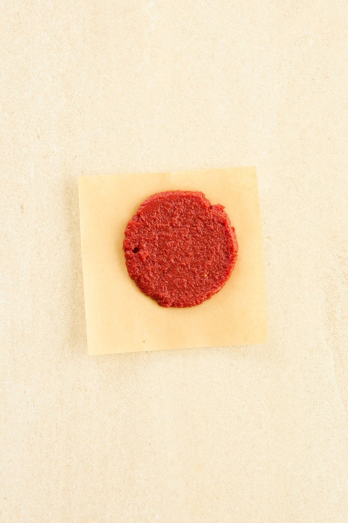 A disc of tomato paste on a piece of parchment paper. 