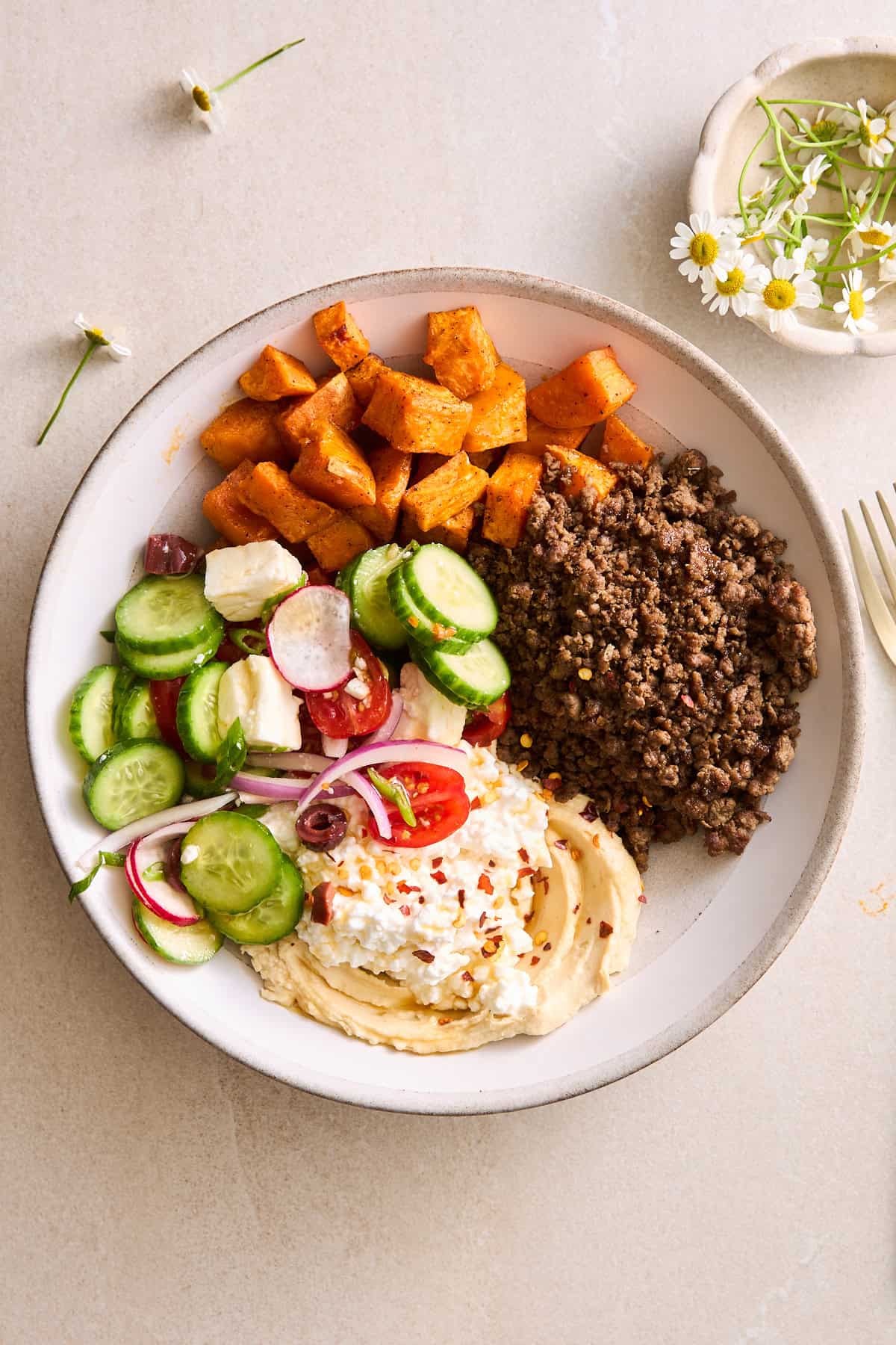 A ground beef bowl with roasted sweet potatoes, fresh veggies, and cottage cheese.