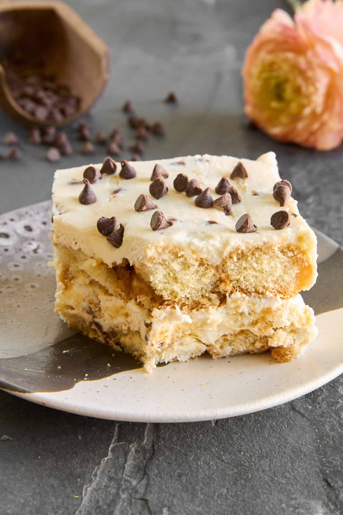 A slice of tiramisu cannoli on a plate missing a bite. 
