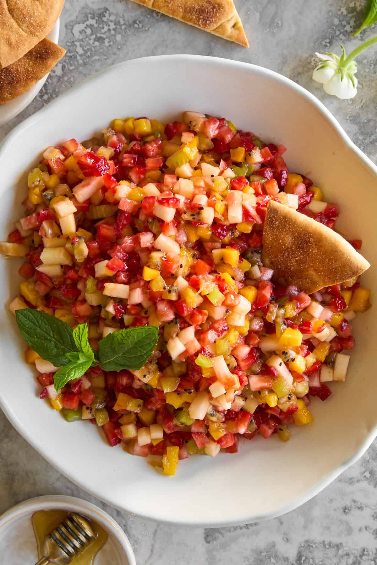 A bowl of fruit salsa with a pita chip sticking out.