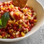 A bowl of fresh fruit salsa with a pita chip sticking out.