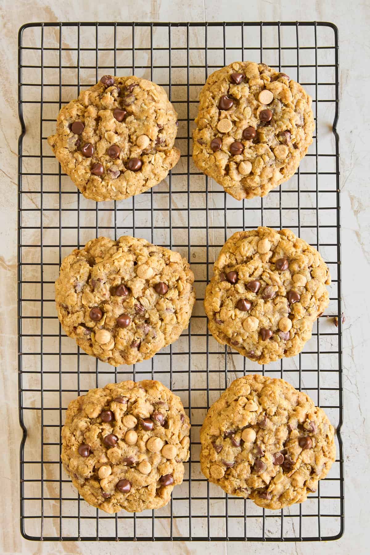 Six baked copycat Crumbl mom's cookies on a wire rack. 