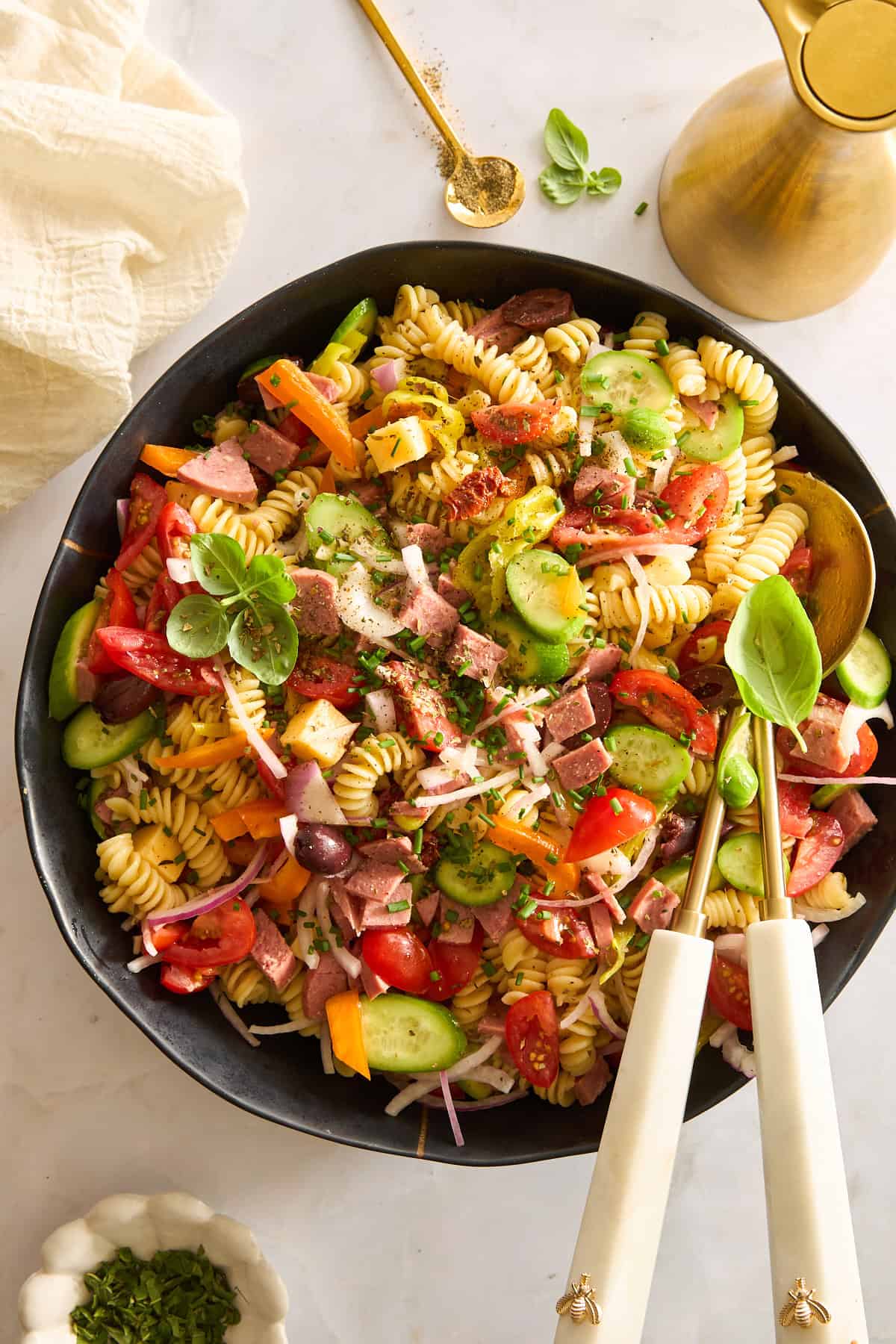 A bowl of Mediterranean pasta salad topped with fresh herbs.