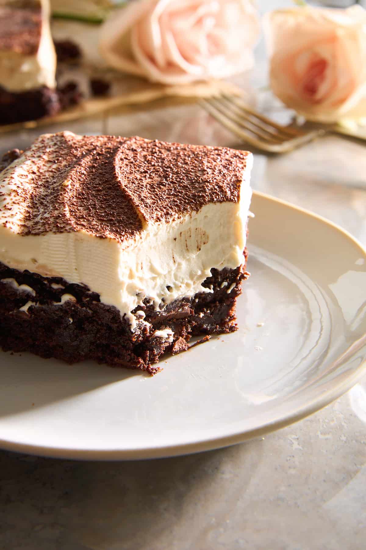 A tiramisu brownie on a plate with a corner bite missing.