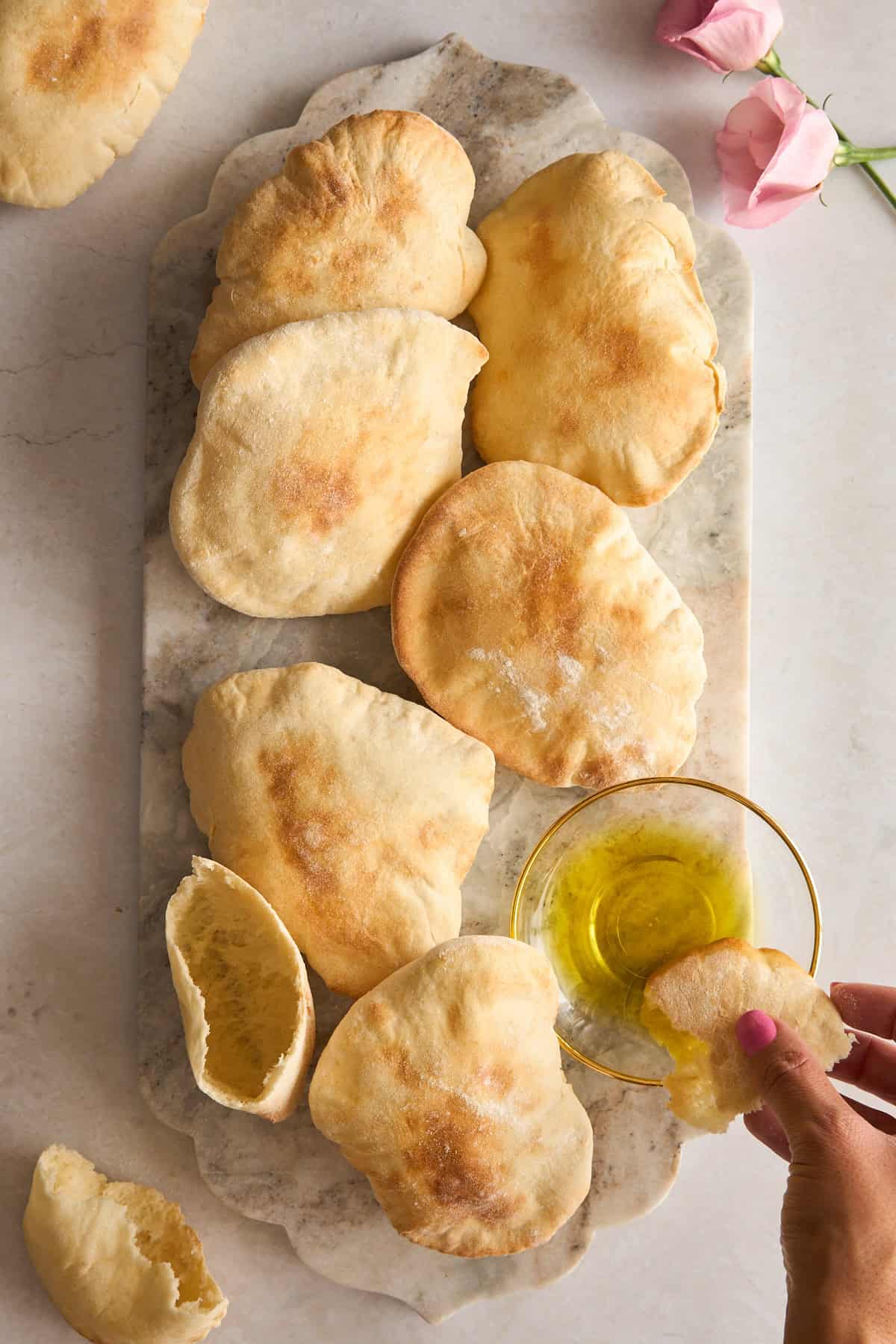 A marble tray topped with several pieces of pita bread sits on a light surface. 