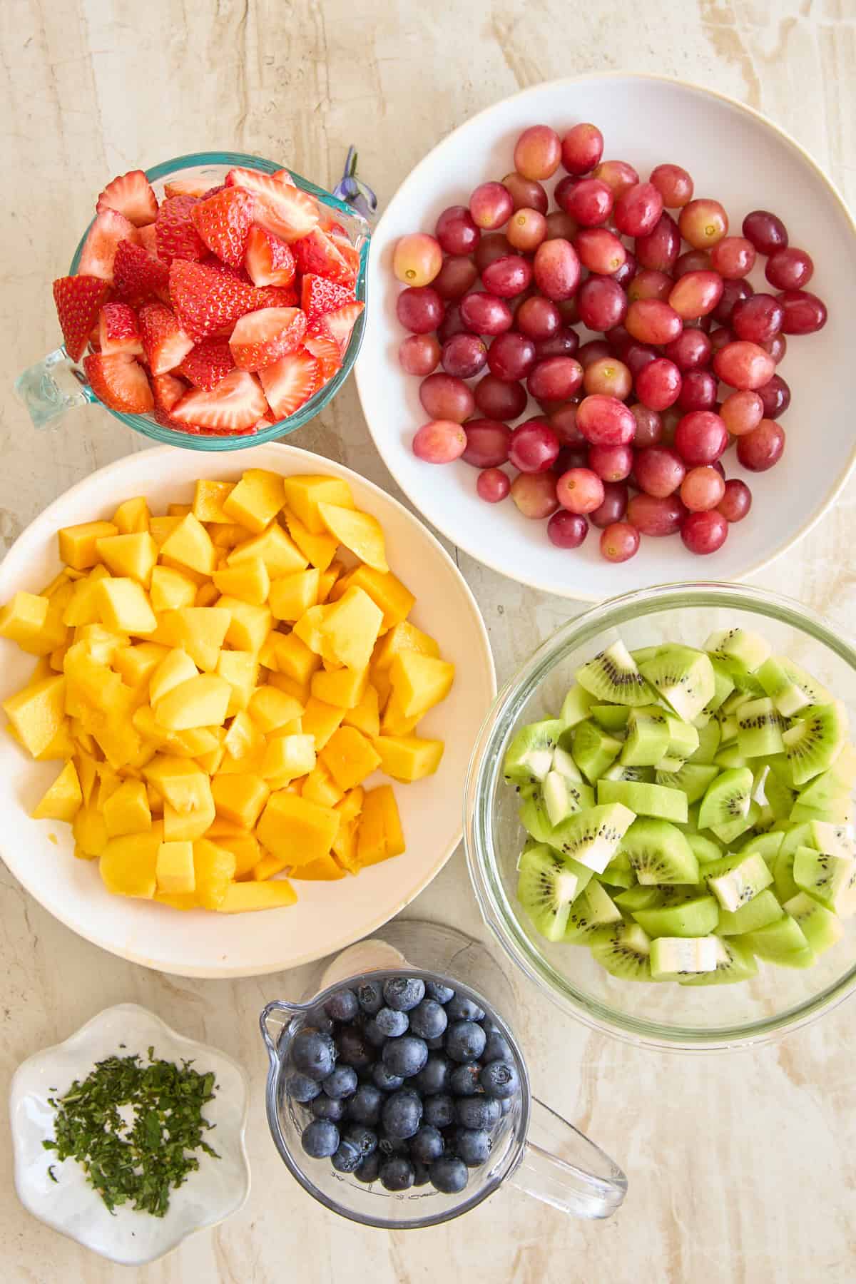 Various fruits on plates and in bowls or a measuring cup